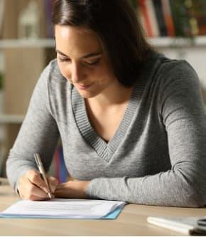 Woman writing on paper at desk